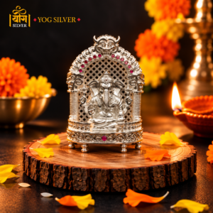 YOG SILVER intricately designed silver Ganesha idol in an ornate shrine with red decorative accents, festive diyas, and marigold flowers.