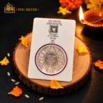 YOG SILVER 100g fine silver coin with intricate floral engraving and premium packaging displayed in a festive Diwali setting.
